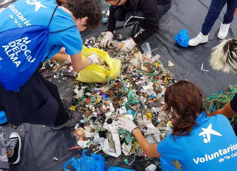 Voluntarios de la Caixa limpian de basura los arenales de Riazor y Orzán