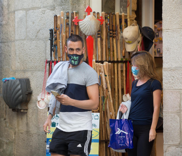 Los peregrinos alicantinos Miguel Ángel y Elena salen de un establecimiento con elementos del Camino a la venta en la localidad de Sarria, mientras los peregrinos retornan al Camino francés de la Ruta Jacobea