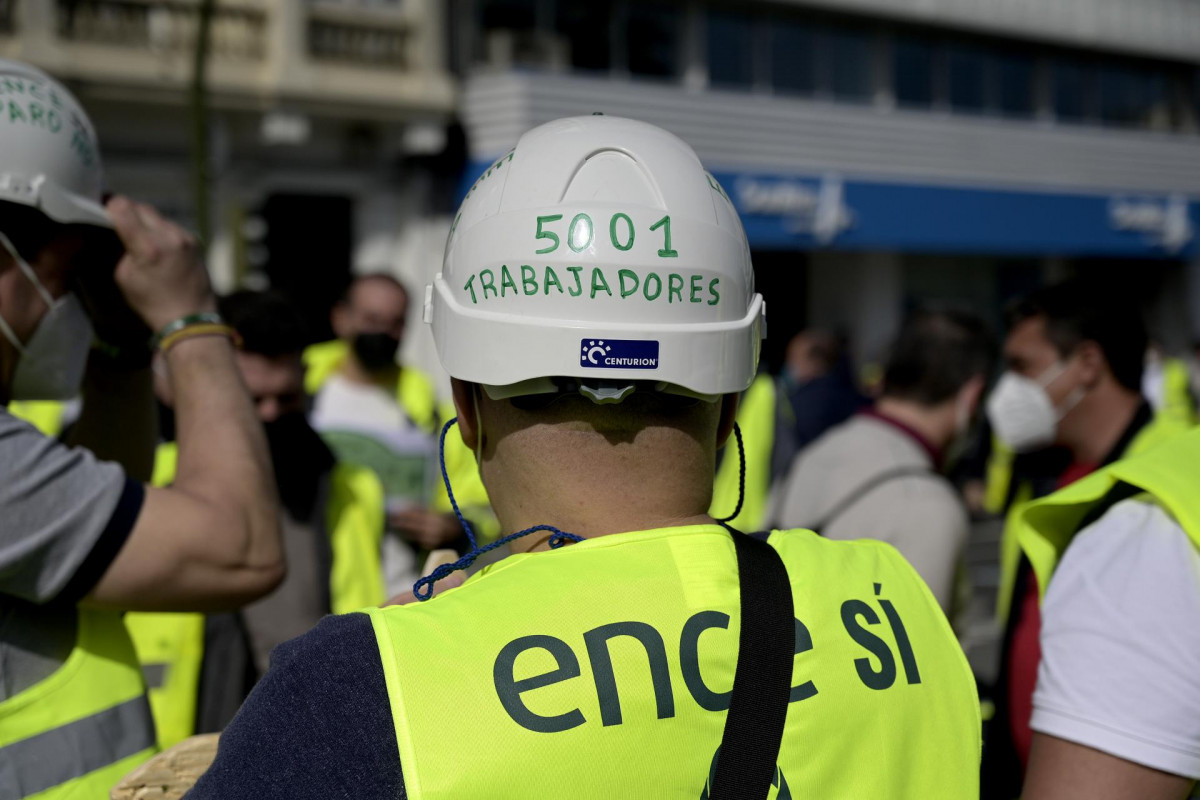 Un trabajador de ENCE Pontevedra con un casco de trabajo y acompañado de transportistas de madera acude a una sentada organizada en A Coruña delante de la Delegación del Gobierno para exigir garant