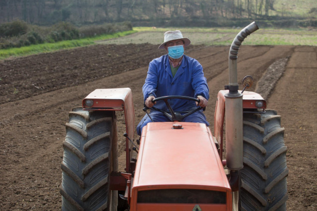 Archivo - Manuel Rodríguez ara sus fincas con el tractor y mascarilla para plantar patatas  en Lugo, Galicia (España), a 24 de marzo de 2021. El sector primario ha sido fundamental durante la pandemia. Agricultores y ganaderos han dado lo mejor de sí mism