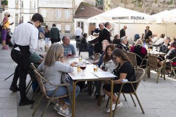 Archivo - Un grupo de turistas consulta una carta en la terraza de un bar en Santiago de Compostela.