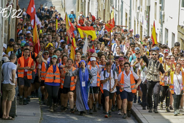 Llegada de jóvenes peregrinos ocupando todo el ancho de la calzada en el Barrio de San Pedro y enarbolando banderas españolas