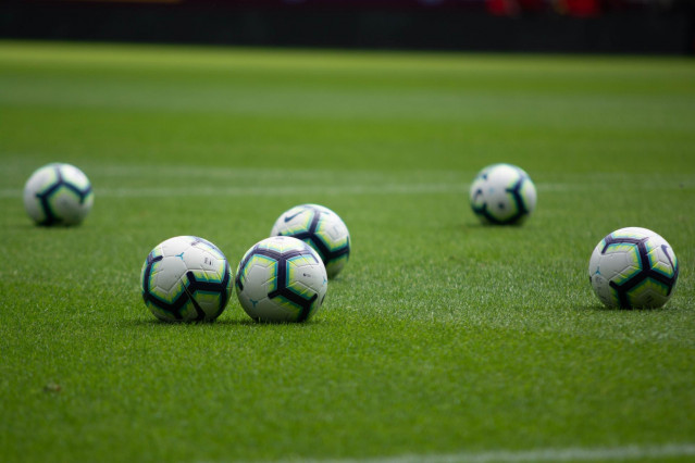 Archivo - Balones de fútbol en un campo