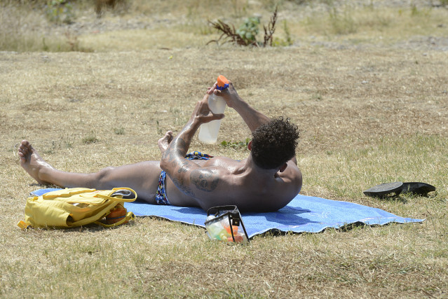 Archivo - Un hombre toma el sol en la zona piscinas de Oira, a 12 de julio de 2022, en Orense, Galicia (España). Los termómetros de la práctica totalidad del territorio gallego alcanzarán valores “extremos” debido a la ola de calor que comenzó la semana p