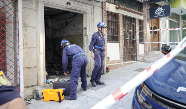 Dos agentes de Policía trabajan en el edificio incendiado en Vigo en la madrugada del 11 de octubre de 2023, en el que murieron una madre y tres de sus hijos.