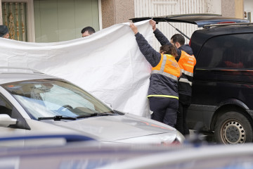 Dos agentes de Protección Civil tapan con una lona la zona donde se han encontrado los cuerpos de dos octogenarios en Sigüeiro.