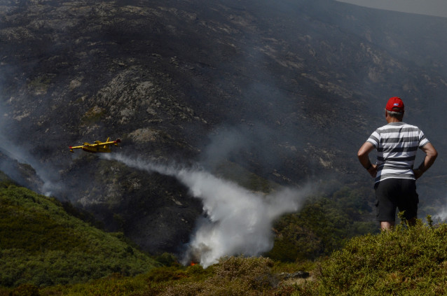 Archivo - Un vecino de Senderiz en Lobeira observa un hidroavión trabajar en el incendio forestal en la Serra do Leboreiro, sobrevuela una explotación ganadera, en el parque natural de Baixa Limia e Serra do Xurés, a 26 de agosto de 2022, en Serra do Xuré