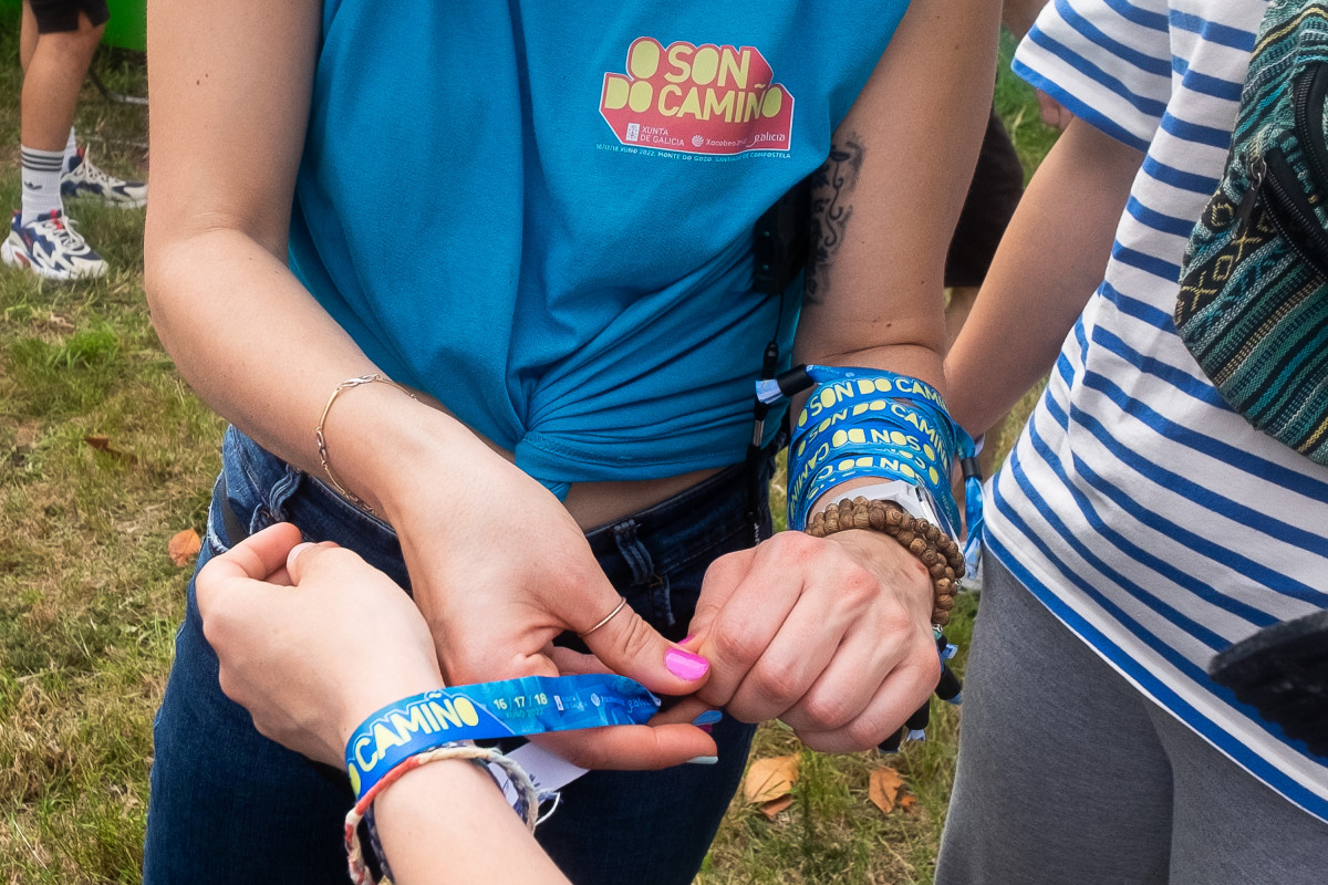 Archivo - Una chica pone una pulsera en la zona de acampada en el festival Oson de Camiño, en el Monte do Gozo, a 15 de junio de 2022, en Santiago de Compostela, A Coruña