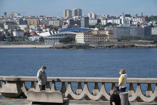 Archivo - Dos personas pasean por el paseo marítimo de A Coruña (Galicia), con el estadio de Riazor de fondo, en el segundo día en que el Gobierno permite salir a hacer deporte de forma individual y pasear con otra persona con la que se conviva, a determi