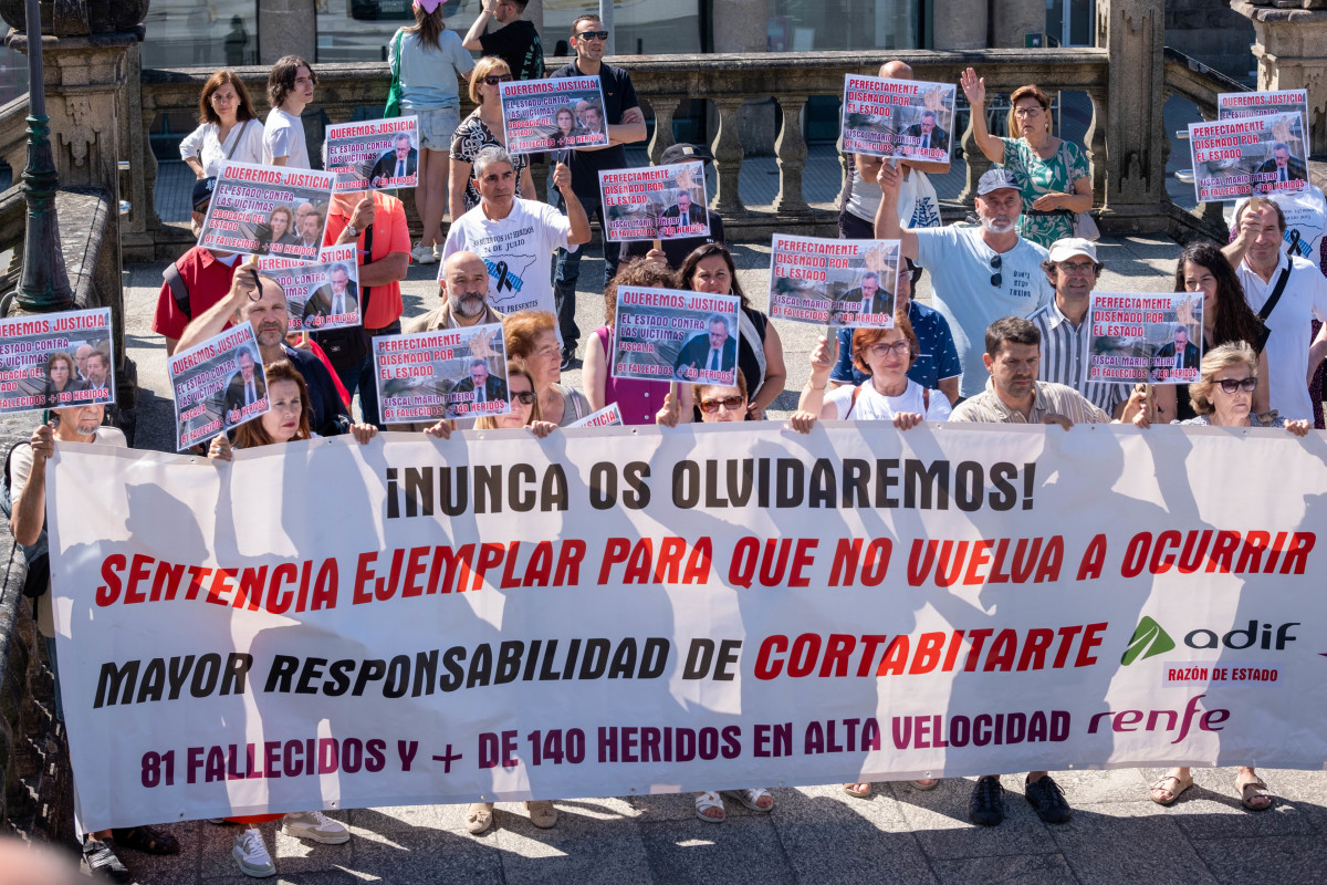 Varias personas con una pancarta y carteles durante una concentración de las víctimas de Angrois, en la estación de tren de Santiago, a 24 de julio de 2024, en Santiago de Compostela, A Coruña, Ga