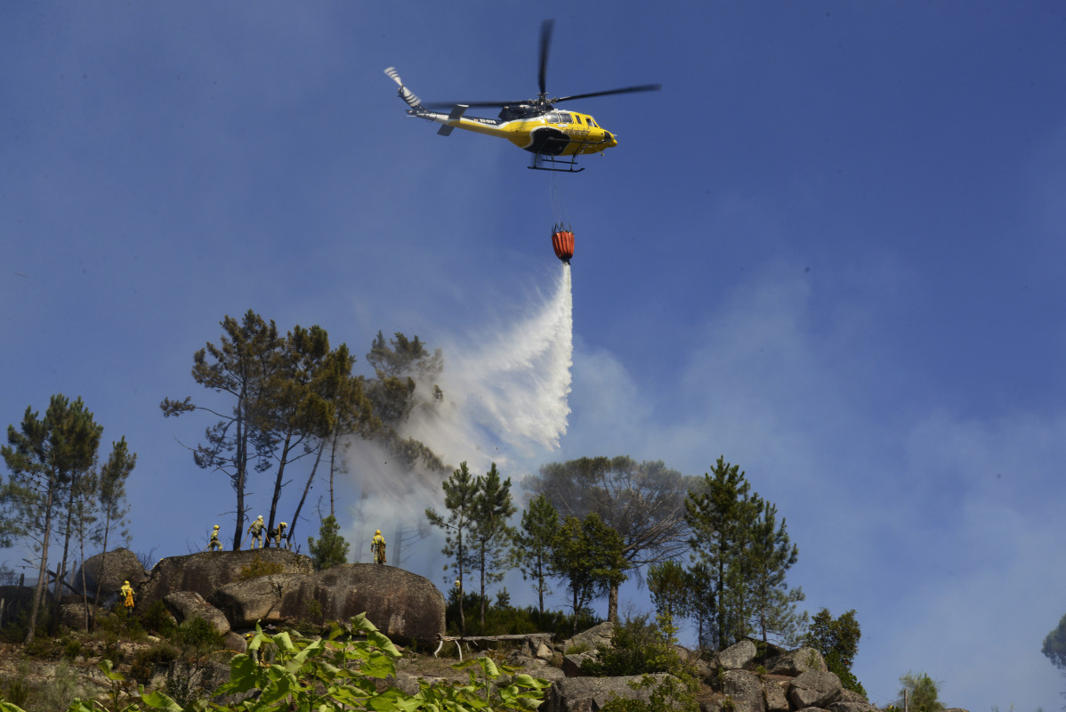 Archivo - Un helicóptero arroja agua sobre un incendio forestal, a 28 de julio de 2021, en la parroquia de Santa Mariña do Monte, Ourense, Galicia (España). Un total de seis aviones y dos helicópt