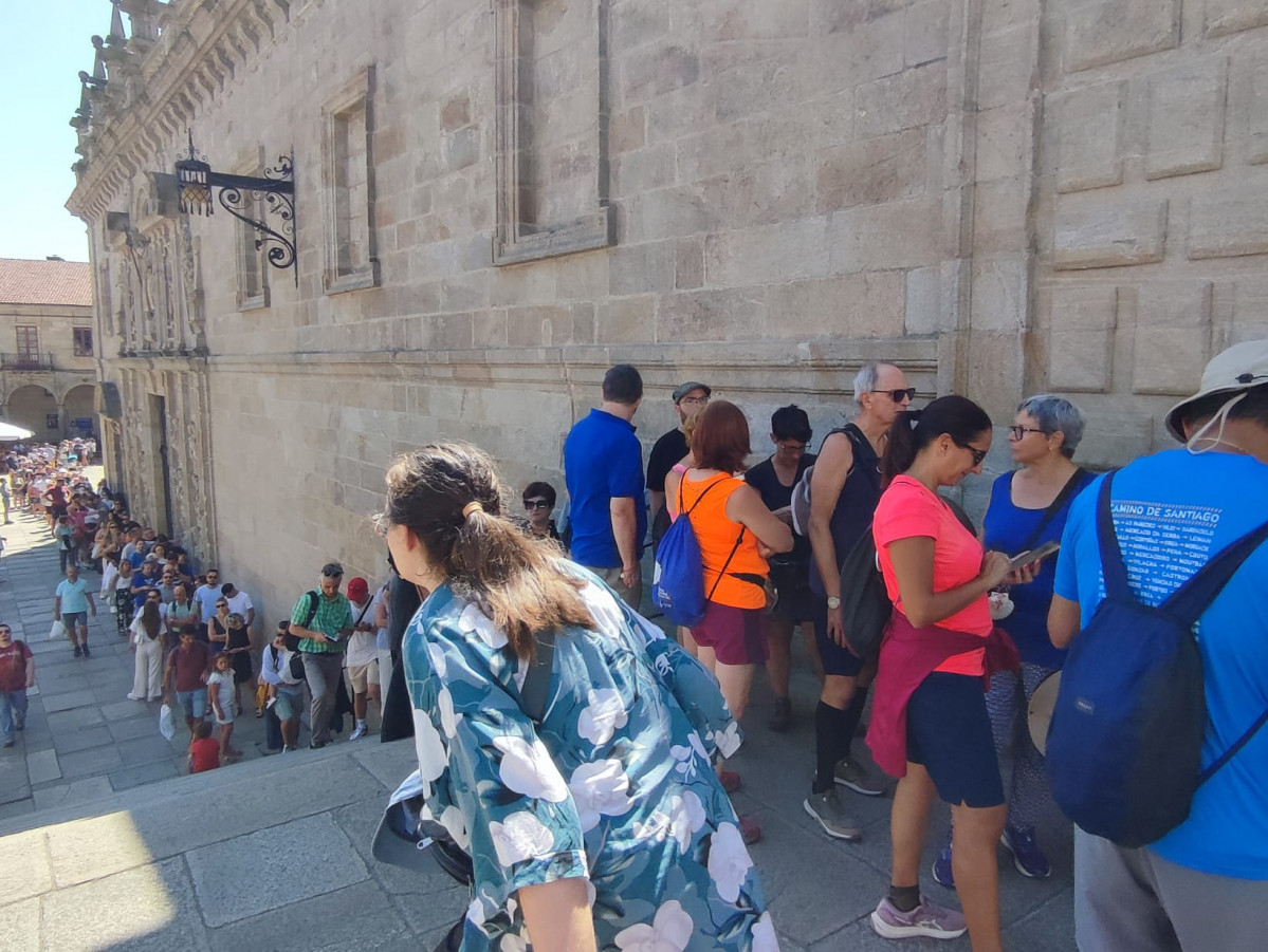 Centenares de peregrinos y turistas en la larga cola que atraviesa la escalinata de la Praza de la Quintana ayer para entrar a la Catedral