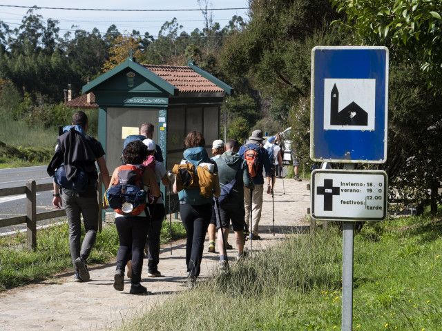 Archivo - Un grupo de peregrinos pasa frente a un cartel que indica el horario de misas mientras realizan el Camino de Santiago, en Santiago de Compostela, a 9 de octubre de 2021, en Santiago de Compostela, A Coruña, Galicia (España).