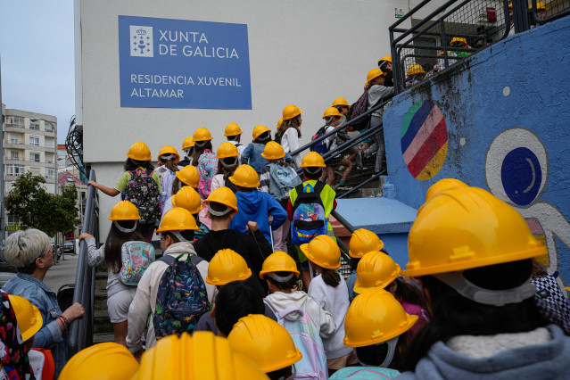 Imagen de niños accediendo al centro con cascos de protección.