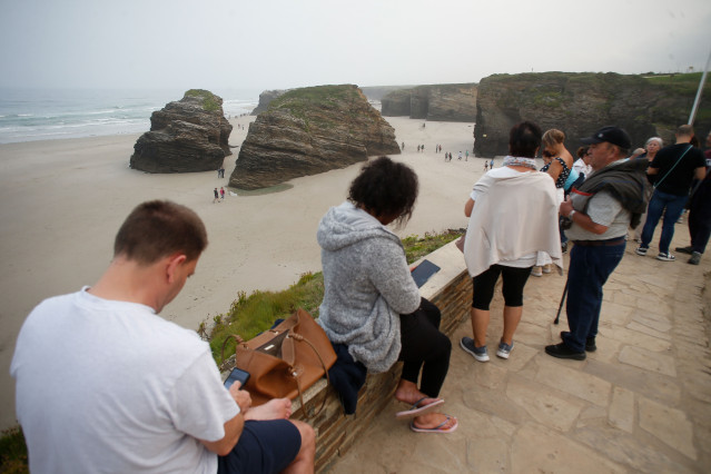 Varias personas pasean durante la bajamar en la playa de As Catedrais