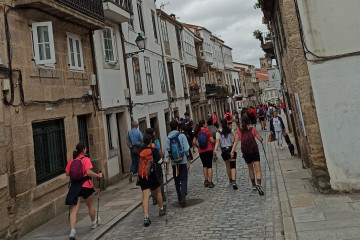 Archivo - Peregrinos bajan por el medio de la Rúa de San Pedro, en Santiago de Compostela