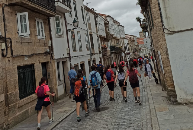 Archivo - Peregrinos bajan por el medio de la Rúa de San Pedro, en Santiago de Compostela