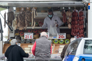 Archivo - Un hombre y una mujer compran en un mercadillo de Castro Riberas de Lea, Galicia (España) a 27 de enero de 2021. A las 00,00 de este miércoles han entrado en vigor las nuevas restricciones