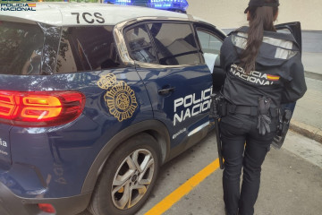 Una agente de la Policía Nacional junto a un coche patrulla.