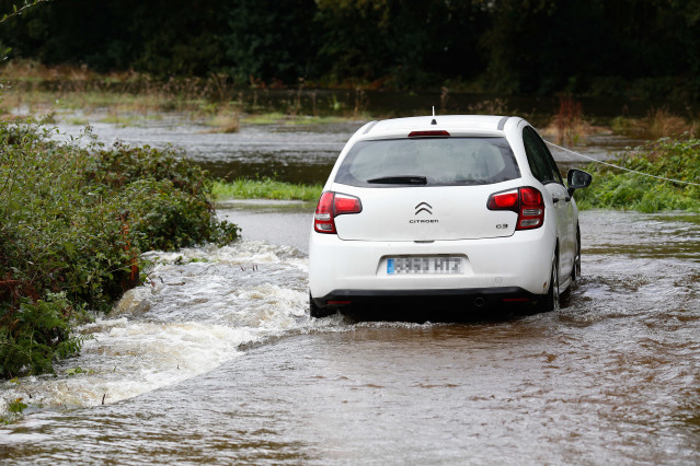 Un coche circula por un camino anegado por el desbordamiento del río Anllo, a 9 de octubre de 2024, en A Veiga, Abadín, Lugo, Galicia (España). La Agencia Estatal de Meteorología (AEMET) ha puesto a Galicia en alerta naranja por la borrasca Kirk, que prov