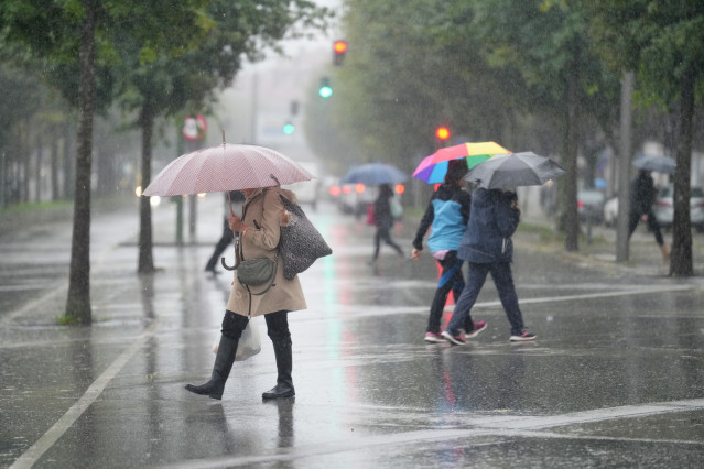 Varias personas caminan bajo la lluvia.