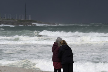 Archivo - Dos mujeres observan las olas durante el frente meteorológico, a 23 de febrero de 2024, en A Coruña, Galicia (España). La Agencia Estatal de Meteorología (Aemet) decretó un aviso naranj