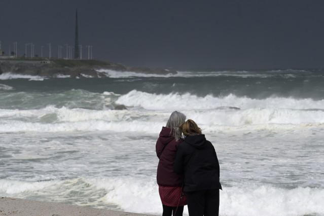 Archivo - Dos mujeres observan las olas durante el frente meteorológico, a 23 de febrero de 2024, en A Coruña, Galicia (España). La Agencia Estatal de Meteorología (Aemet) decretó un aviso naranja por temporal costero en el litoral gallego que ya está act