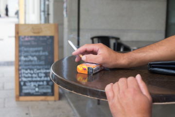 Archivo - Una persona fuma en una terraza durante el primer día de la prohibición de realizarlo en la vía pública en Galicia si no existe una distancia de dos metros de separación con otras perso