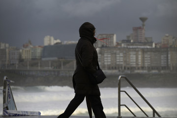 Archivo - Una mujer se cubre con la capucha durante el frente meteorológico, a 23 de febrero de 2024, en A Coruña, Galicia (España).