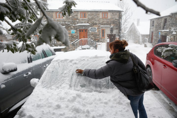 Una mujer limpia la nieve de su coche, a 9 de diciembre de 2024, en Pedrafita do Cebreiro, Lugo, Galicia (España). Un total de 12 comunidades autónomas están hoy en riesgo (alerta amarilla) por nie