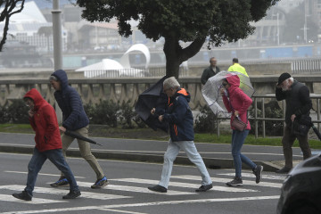 Archivo - Varias personas se protegen de la lluvia y el viento con paraguas, a 20 de octubre de 2023, en A Coruña, Galicia (España). La Xunta ha activado para hoy la alerta roja por temporal costero