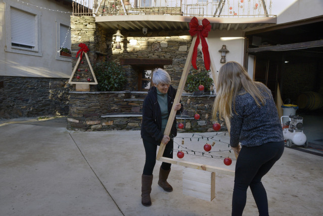 Varios vecinos colocan la decoración navideña, a 23 de diciembre de 2024, en Alvaredos, Quiroga, Lugo, Galicia (España).