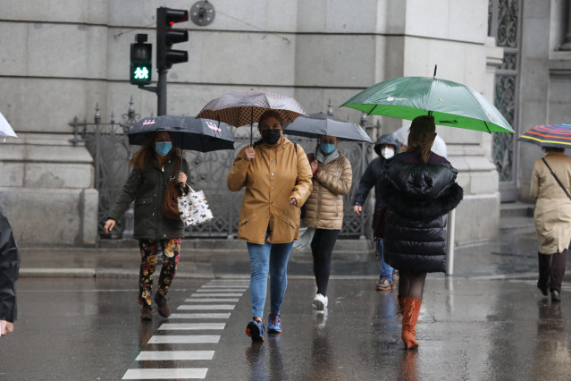 Archivo - Transeúntes caminan por el centro de la capital protegiéndose de la lluvia con paraguas, en Madrid (España), a 20 de octubre de 2020.  Una treintena de provincias estarán este martes 20 de octubre en riesgo naranja (importante) y riesgo amarillo