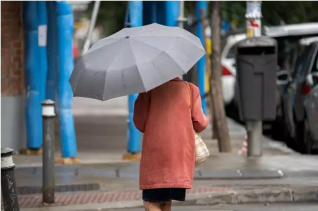 Una mujer pasea por una calle con un paraguas.